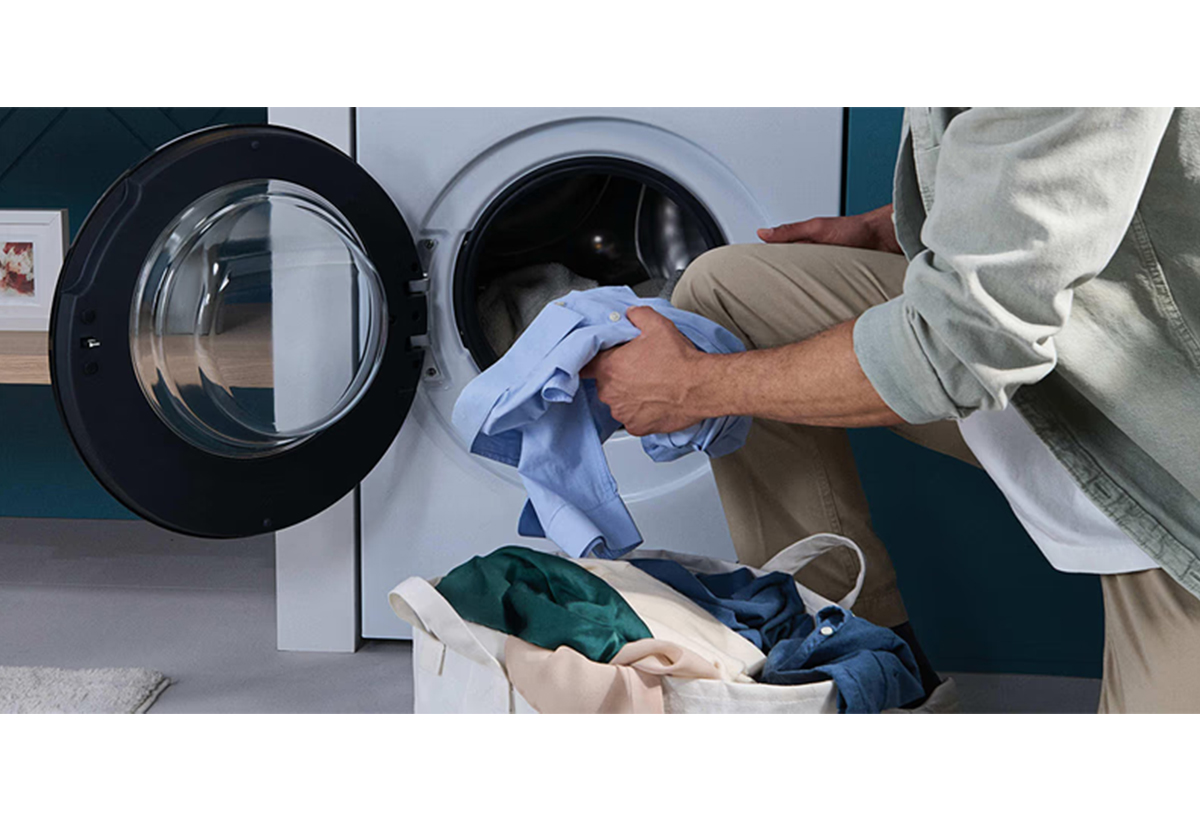 Απεικονίζεται άνδρας να τοποθετεί ρούχα στον κάδο της συσκευής.